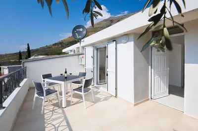 a patio with a table and chairs on a balcony at Dolores Apartments in Petrovac na Moru