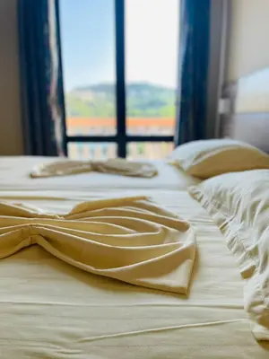 two beds with white sheets and a window at Rooms Ibrocevic in Ulcinj