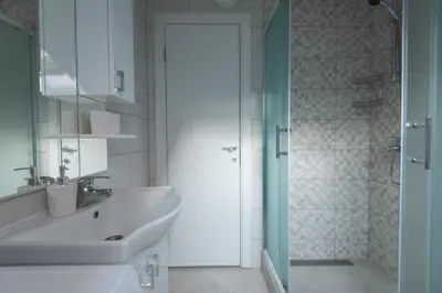 a white bathroom with a sink and a shower at Honey Farm House in Virpazar