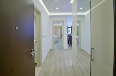 a hallway with white walls and wooden floors and a door at Brand New Apartments - free parking in Sveti Stefan
