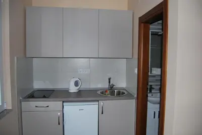 a small kitchen with white cabinets and a sink at Kod Nade in Petrovac na Moru