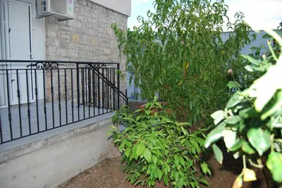 a iron fence next to a bush next to a house at Kod Nade in Petrovac na Moru