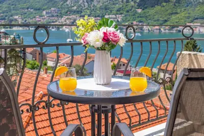 a table with a vase of flowers and two glasses of orange juice at Antonella in Kotor