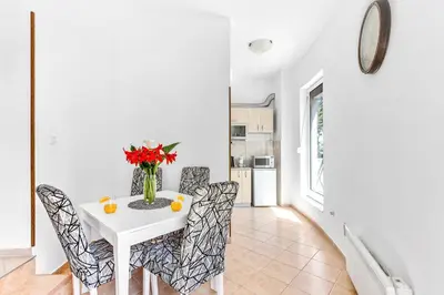 a white dining room with a white table and chairs at Antonella in Kotor