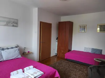a bedroom with two beds with pink sheets at Stan u centru in Podgorica