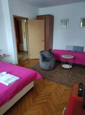 a bedroom with a pink bed and a chair at Stan u centru in Podgorica