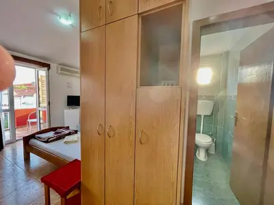a bathroom with a toilet and a wooden cabinet at Vila L Budva in Budva