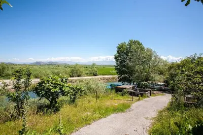 a dirt road next to a river with mountains in the background at Luxury House Petrovic - Vranjina Skadar Lake in Podgorica