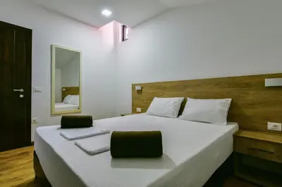 a bedroom with a large white bed with two chairs at Apartmani Djurovic in Ulcinj