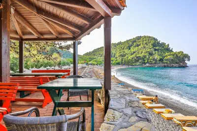 a patio with a table and chairs on the beach at Hotel Plaza Lucice in Petrovac na Moru