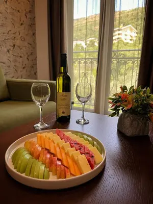a plate of fruit on a table with a bottle of wine at Hotel Plaza Lucice in Petrovac na Moru