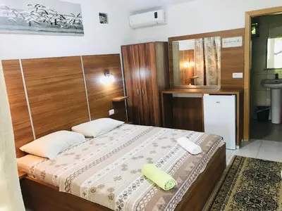 a bedroom with a large bed with a wooden headboard at Flamingo Cottage in Ulcinj