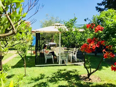 a woman sitting in a gazebo in a garden at Flamingo Cottage in Ulcinj