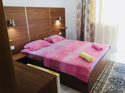 a bedroom with a bed with pink sheets and pink pillows at Flamingo Cottage in Ulcinj