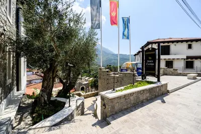 a building with flags and a tree in a courtyard at Stara Čaršija Hotel & SPA in Bar