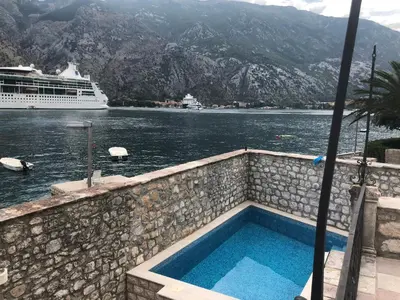 a swimming pool with a cruise ship in the water at Luxury Waterfront Villa with Private Pool and Private Beach for 12 People in Kotor
