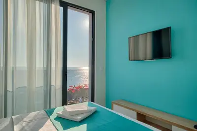 a room with a blue wall with a window and a television at Hotel Obala in Dobra Voda