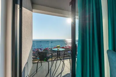a balcony with a table and a view of the ocean at Hotel Obala in Dobra Voda