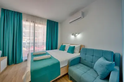 a bedroom with a bed and a blue couch at Hotel Obala in Dobra Voda