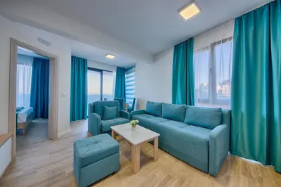 a living room with a blue couch and two chairs at Hotel Obala in Dobra Voda