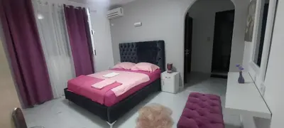 a bedroom with a pink bed and a purple stool at Studio Apartments Jupo in Ulcinj