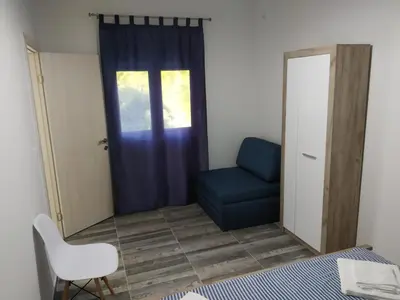 a bedroom with a blue chair and a window at Take a Lake - Zabes, Virpazar in Virpazar