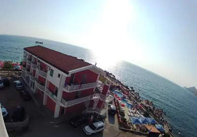 a building next to the water with a group of people at Apartments Atlantis in Dobra Voda