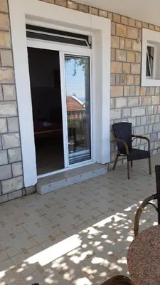 a patio with a sliding glass door and a chair at Apartments Dragišić in Sveti Stefan