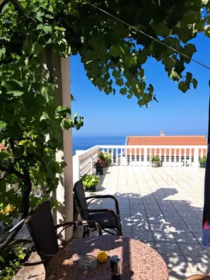 a table and chairs on a patio with a view of the ocean at Apartments Dragišić in Sveti Stefan