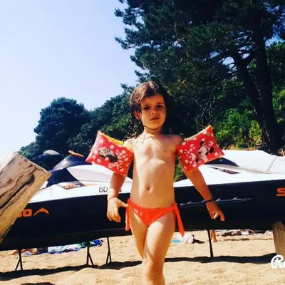 a young boy standing on the beach with a surfboard at Apartments Dragišić in Sveti Stefan