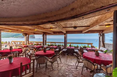 a restaurant with tables and chairs with the ocean in the background at Hotel Savojo in Petrovac na Moru