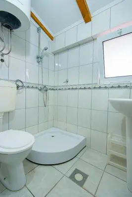 a white bathroom with a toilet and a sink at Vila Vukotić in Petrovac na Moru
