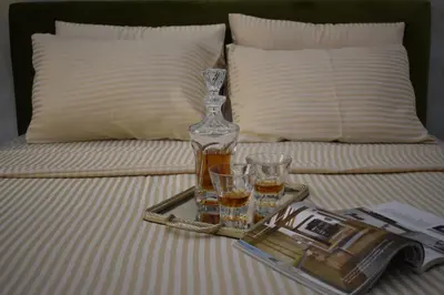 a tray with a bottle and two glasses on a bed at Art Apartments in Kotor