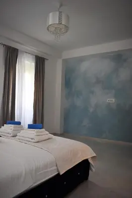 a bedroom with a bed with white sheets and a blue wall at Art Apartments in Kotor