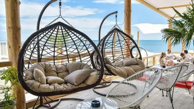 two swings on a patio with the beach in the background at Apartman Danilo in Ulcinj