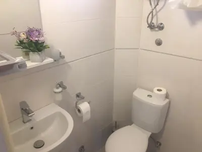 a white bathroom with a toilet and a sink at Apartman Danilo in Ulcinj
