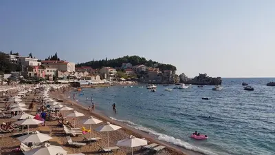 a beach with umbrellas and people in the water at One bedroom apartment Ljilja in Sveti Stefan