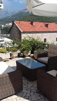 a patio with wicker chairs and a table with a view at Apartments StellaMar in Sveti Stefan