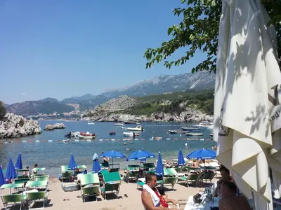 a group of people on a beach with chairs and umbrellas at Apartments StellaMar in Sveti Stefan