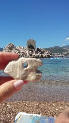 a person holding a rock in front of a beach at Apartments StellaMar in Sveti Stefan