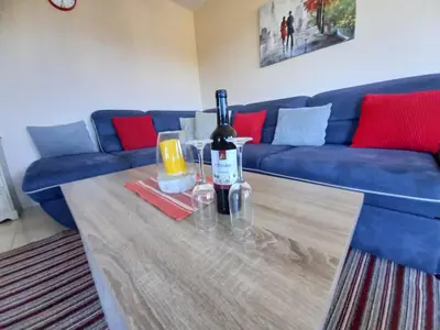 a blue couch with a table with a bottle of wine at Liza Apartment in Ulcinj