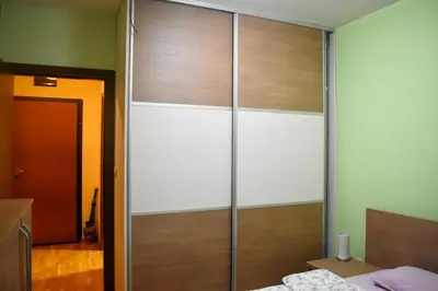 a bedroom with a glass closet with a bed at Apartman Sara 2 in Podgorica