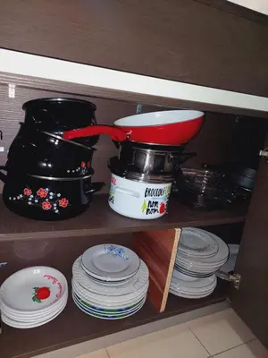 a shelf with a pot and a stack of plates at Apartman Sara 2 in Podgorica