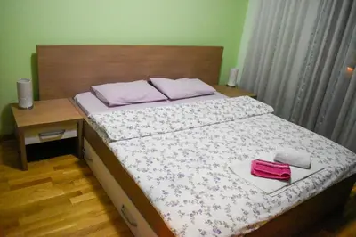 a bedroom with a bed with a wooden head board at Apartman Sara 2 in Podgorica