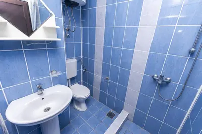 a blue tiled bathroom with a toilet and a sink at Apartments Aleksandar in Ulcinj