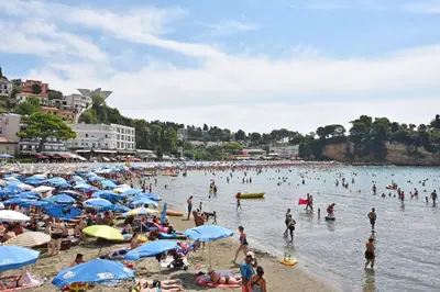 a crowd of people on a beach with blue umbrellas at Apartments Aleksandar in Ulcinj