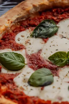 a pizza with basil leaves on top of it at Le Petit Chateau in Bar