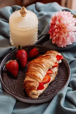 a plate with a croissant and strawberries on a table at Le Petit Chateau in Bar