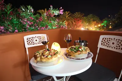 a table with two plates of food and two glasses of wine at Le Petit Chateau in Bar