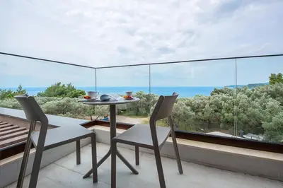 a table and chairs on a balcony with a view of the ocean at Adria lux apartmens 2 in Sveti Stefan